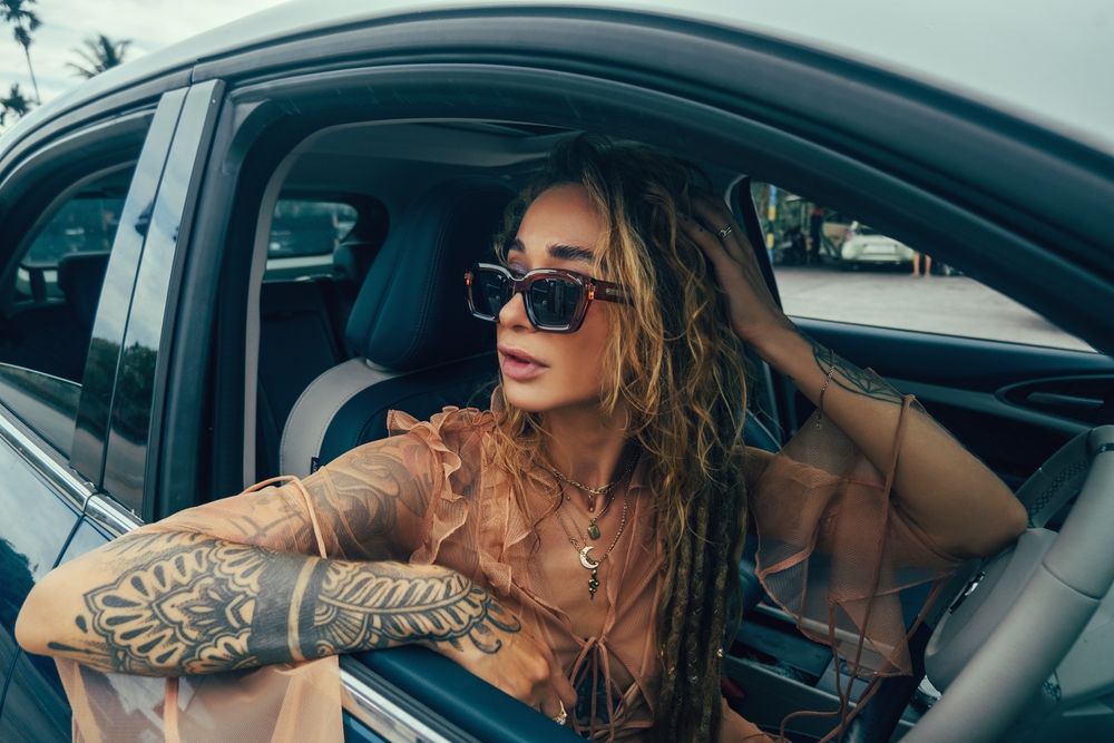 A girl wear a sunglasses while sitting in the car